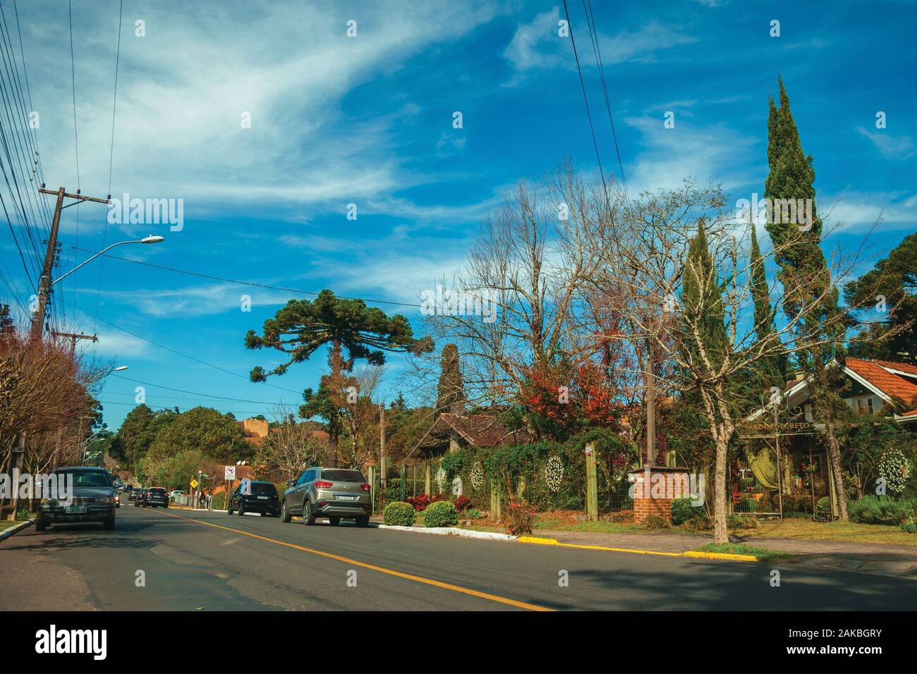Begrünte Häuser und Bäume auf leere gepflasterte Strasse mit parkenden Autos, an einem sonnigen Tag bei Gramado. Ein niedliches europäisch geprägten Stadt im südlichen Brasilien. Stockfoto