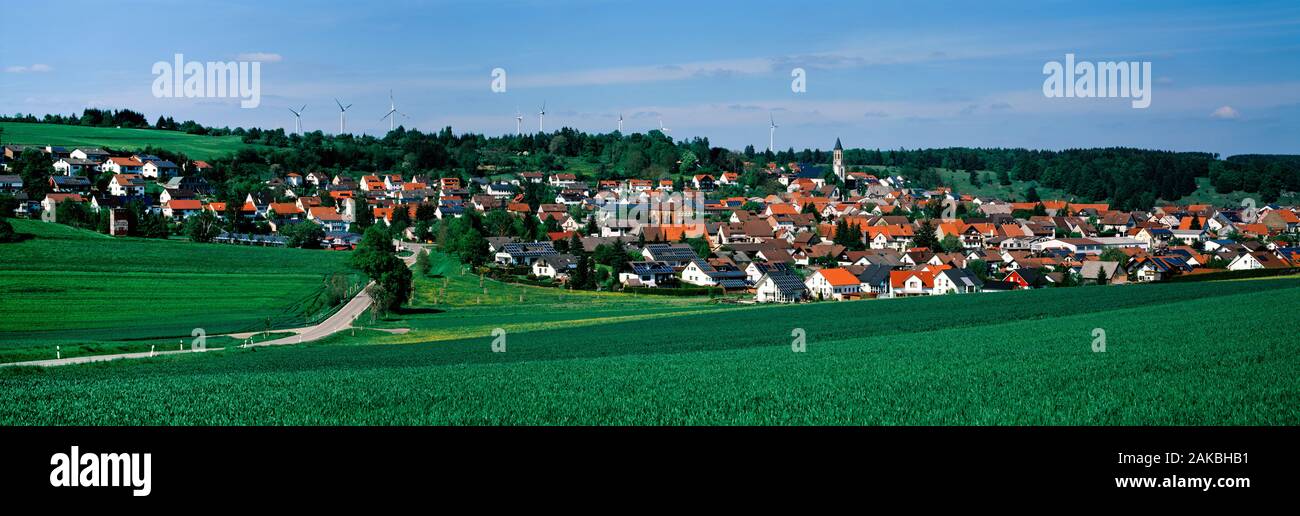 Windenergieanlagen und Dorf inmitten von Feldern in der Nähe von Stuttgart, Deutschland Stockfoto