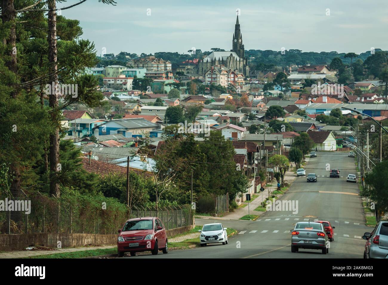 Straße mit Autos Richtung Stadtbild der Häuser und der Kirchturm in Canela. Eine charmante kleine Stadt im Süden Brasiliens. Stockfoto