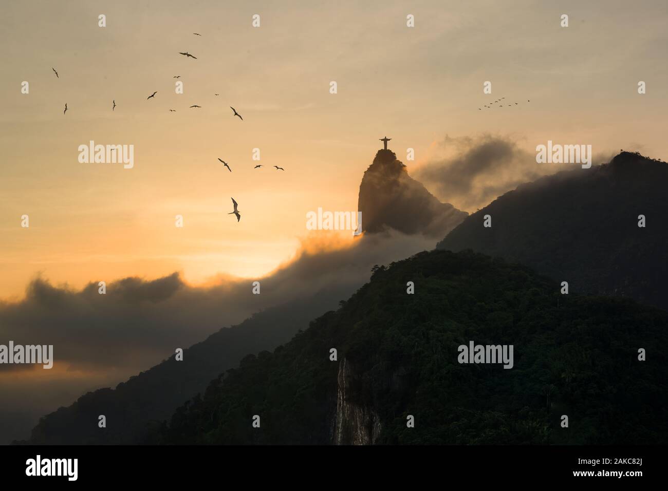 Sonnenuntergang in Rio de Janeiro - Fregattvögel im Himmel mit Silhouette von Christus Erlöser steigende aus Nebel im Hintergrund Stockfoto