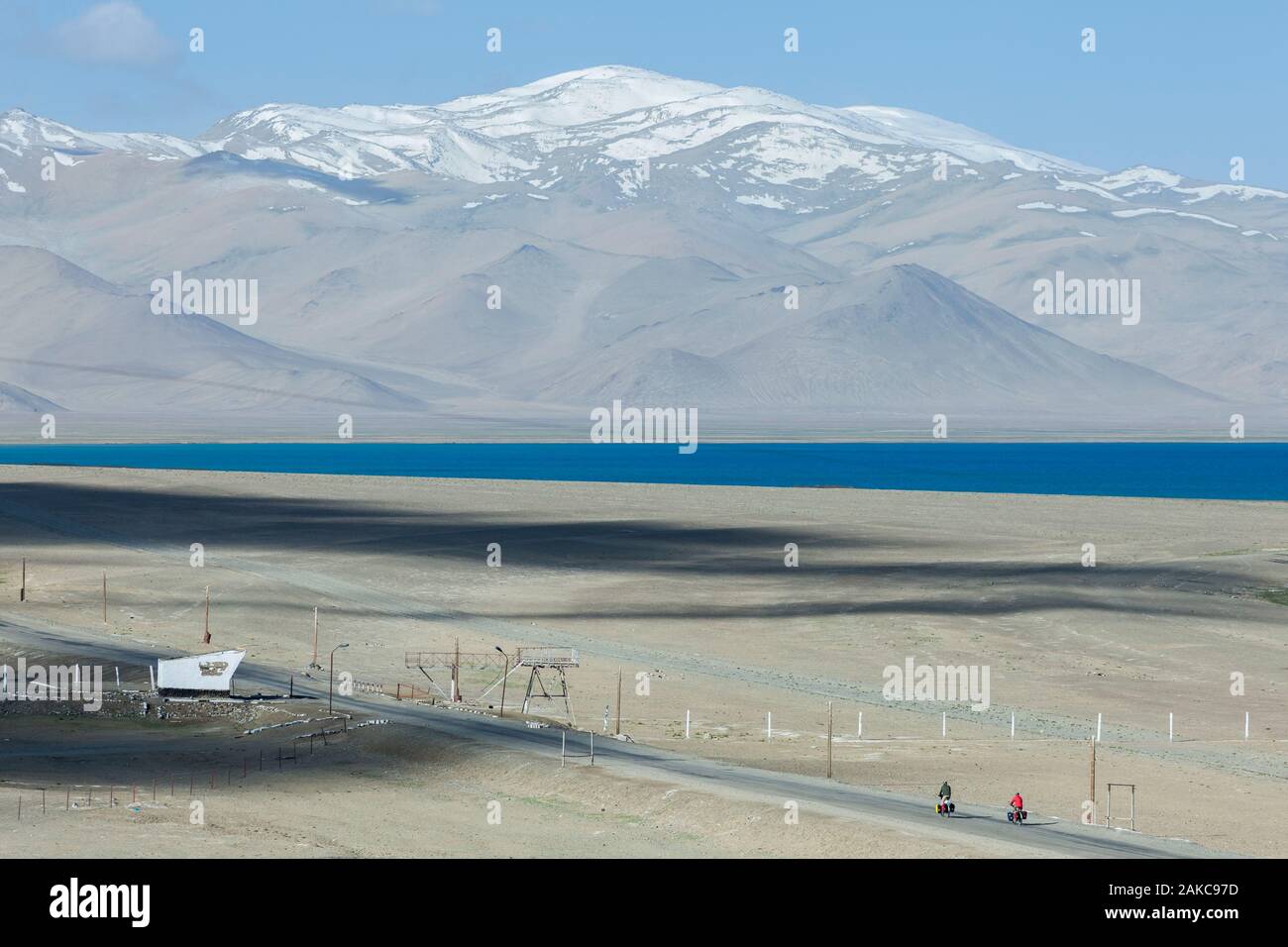 Tadschikistan, Gorno-Badakhshan Autonome Region, Pamir Highway, Karakul, ein paar Western Radfahrer mit Satteltaschen treten auf einer verlassenen Straße ausgestattet, und der See und die Berge im Hintergrund, Höhe 3900 m Stockfoto