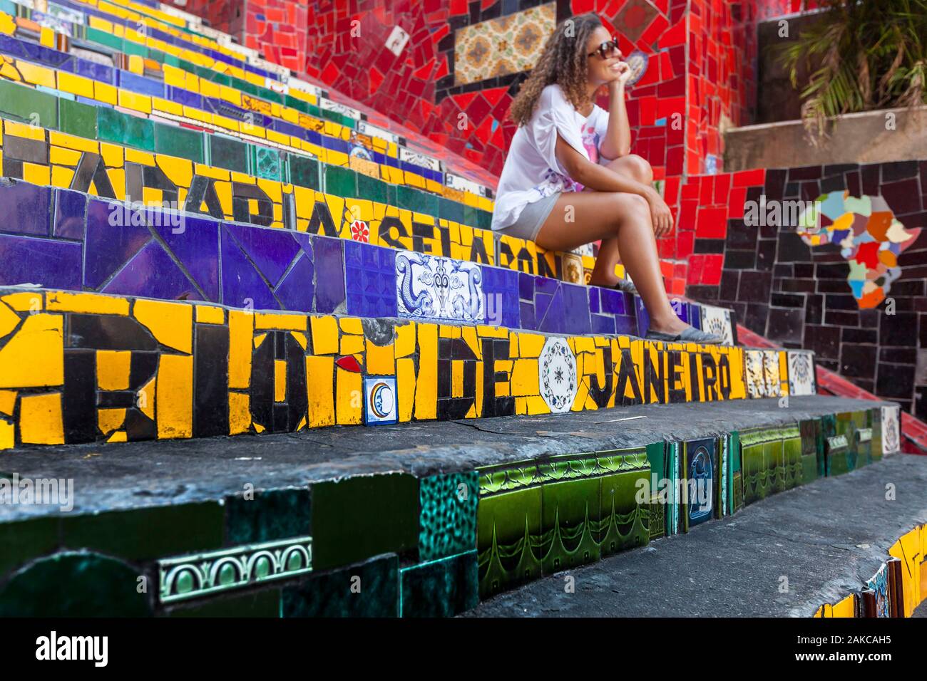 Brasilien, Bundesstaat Rio de Janeiro, die Stadt von Rio de Janeiro, Carioca Landschaften zwischen den Bergen und dem Meer klassifiziert, UNESCO-Weltkulturerbe, Santa Teresa, Treppe mit Fliesen von Künstler Jorge Selarón, junge Frau sitzt auf der Treppe Stockfoto