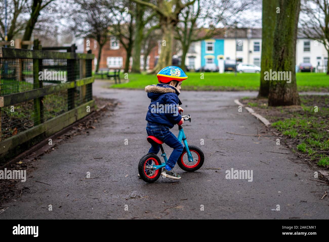 Ein kleiner Junge mit dem Fahrrad durch den Park trägt einen Helm Stockfoto