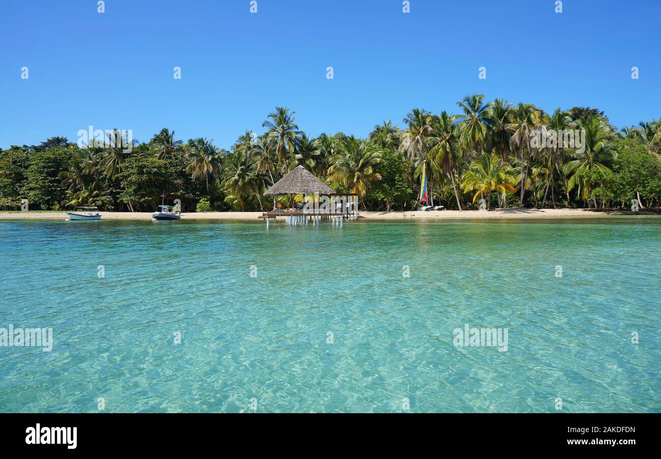 Tropischen Küste mit Kokospalmen und eine Palapa über Wasser, Bocas del Toro, Karibik, Panama, Mittelamerika Stockfoto