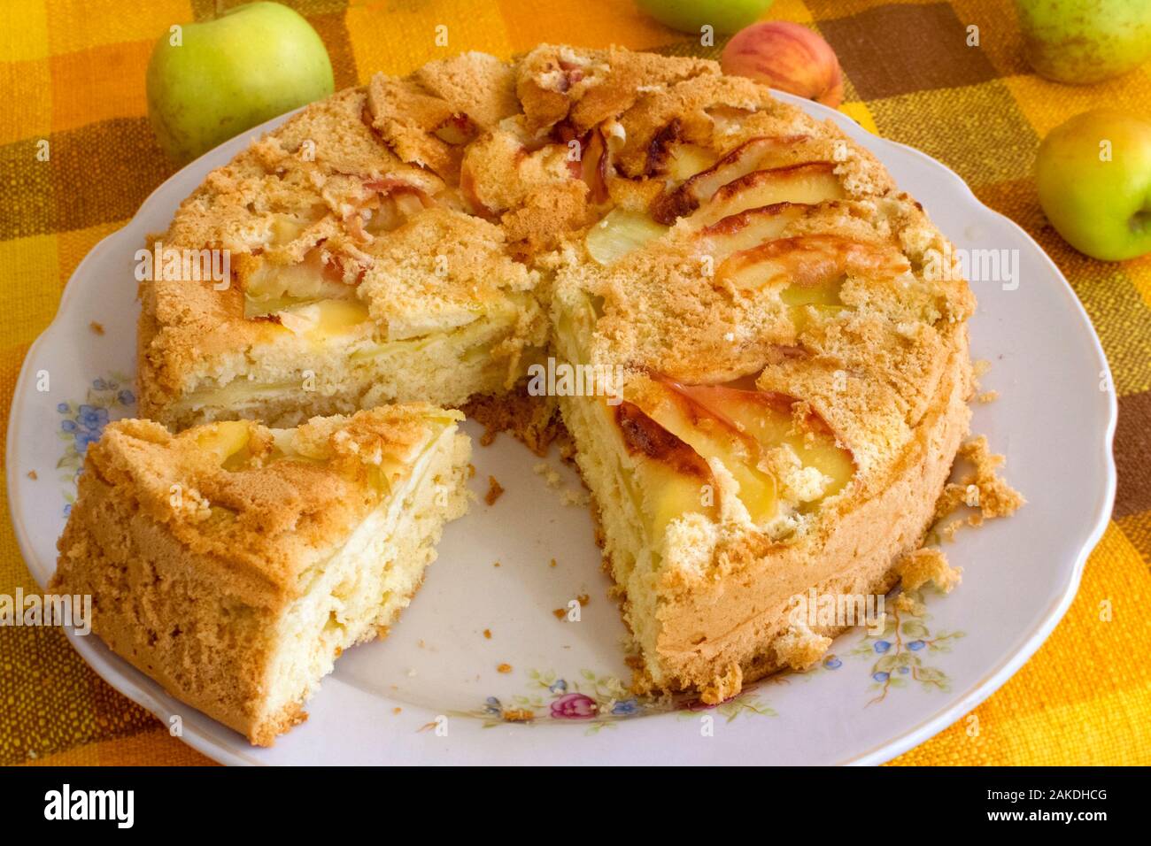 Hausgemachtes Gebäck für Tee, Apfelkuchen, Keks Teig. Schneiden Sie Kuchen mit Äpfeln auf eine Platte auf eine gelbe Tischdecke Hintergrund. Stockfoto