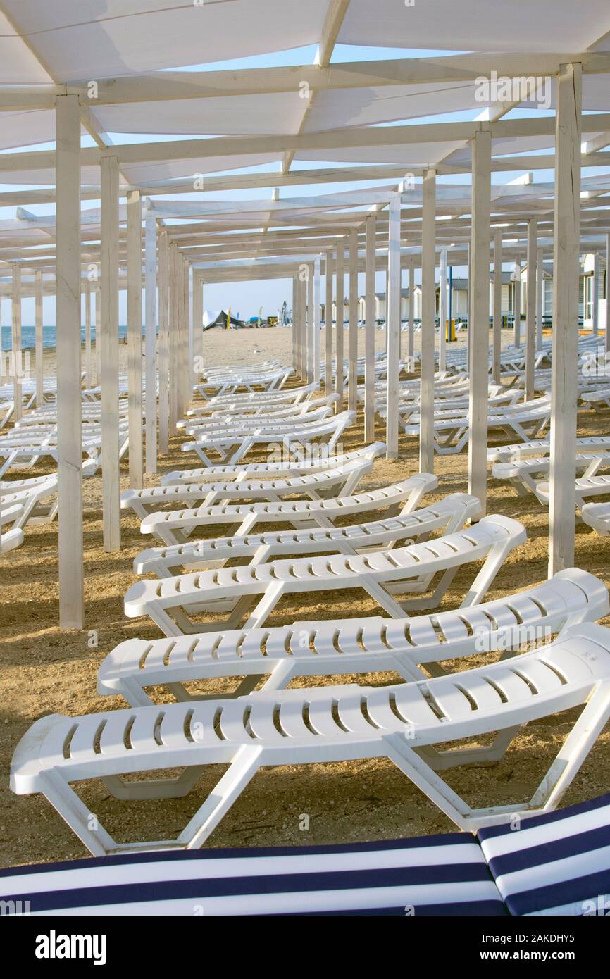 Weißen chaiselounges stehen in einer Reihe auf einem Sandstrand, Perspektive. Sommer, Urlaub am Meer Stockfoto
