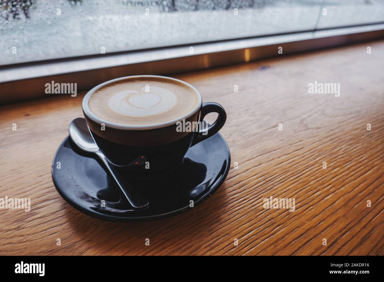 An einem regnerischen Tag in Taipei, Taiwan, steht ein gedämpfter Espresso aus Hafermilch am Fenster Stockfoto