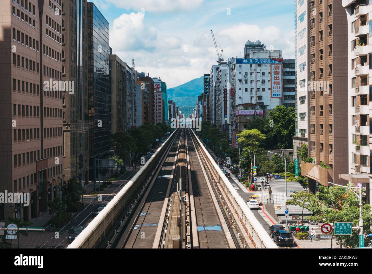 Wenn Sie einen erhöhten Streckenabschnitt zwischen den Gebäuden hinunterschauen, fahren Sie mit der Metro Taipeh am Bahnhof Daan Stockfoto