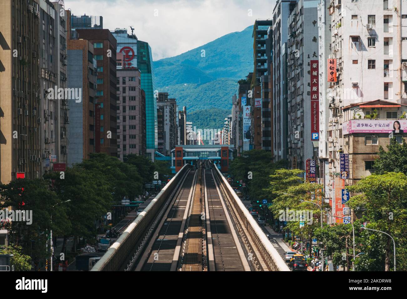 Wenn Sie einen erhöhten Streckenabschnitt zwischen den Gebäuden hinunterschauen, fahren Sie mit der Metro Taipeh am Bahnhof Daan Stockfoto