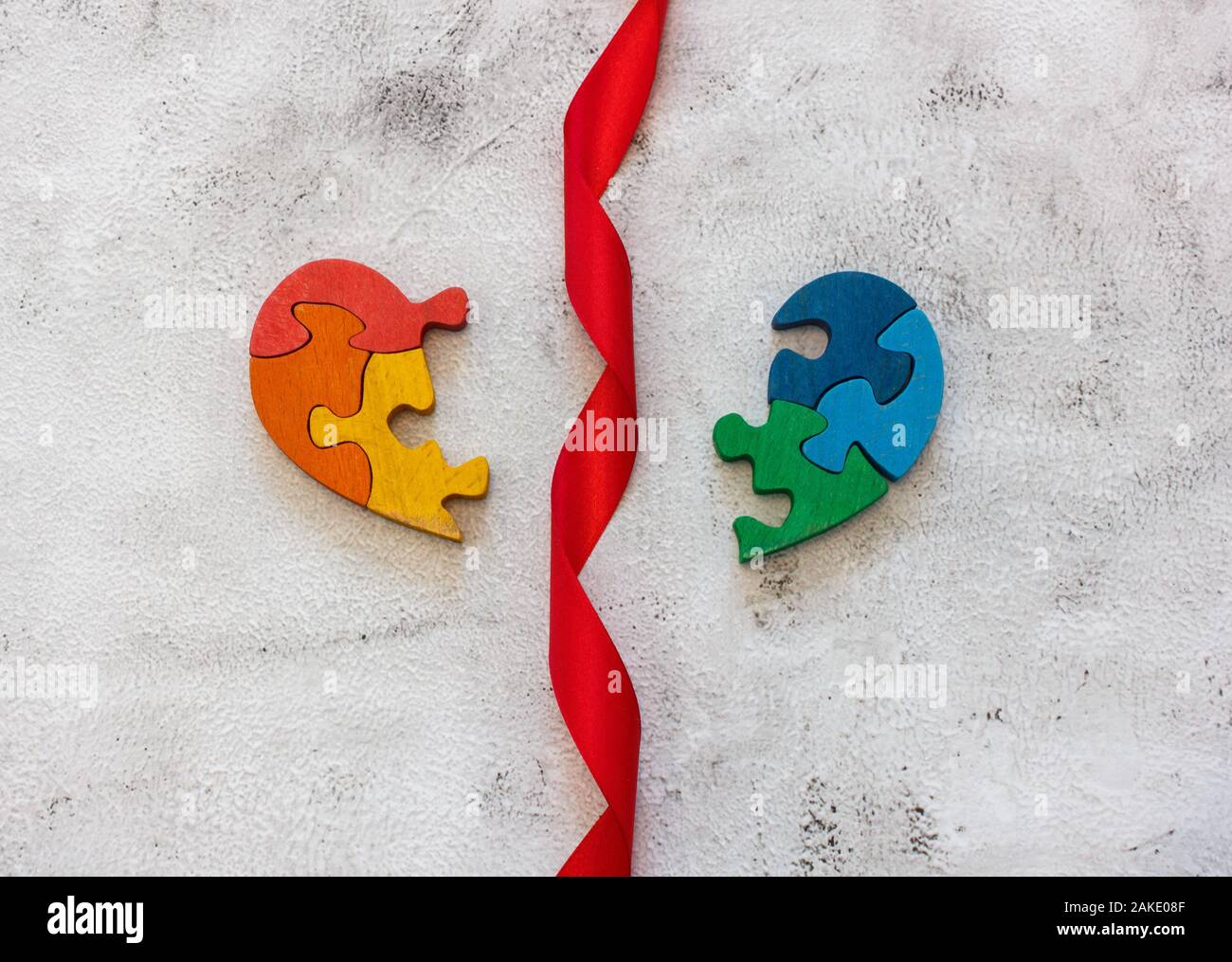 Hölzerne mehrfarbige Puzzle in Form von gebrochenem Herzen auf grauem Hintergrund. Bürokratie. Konzept valentines Tag, Beziehung. Leerzeichen für Text Stockfoto