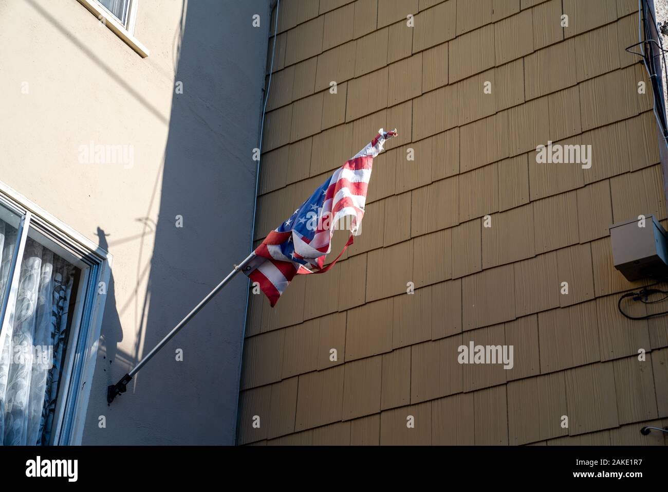Tattered United States amerikanische Flagge vor Suburban Home Stockfoto