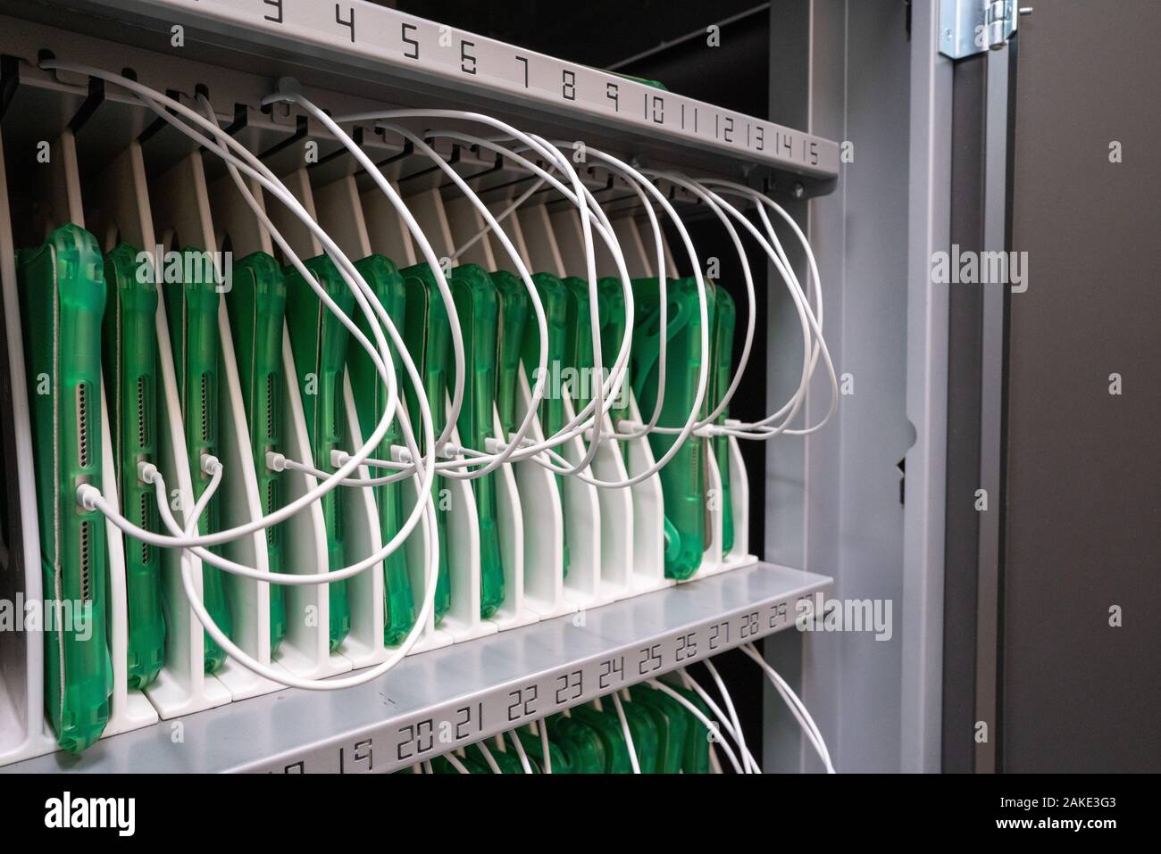 Reihe von Tabletten in Schutzhüllen in einem Schaltschrank in Enterprise office Ort aufgeladen wird Stockfoto