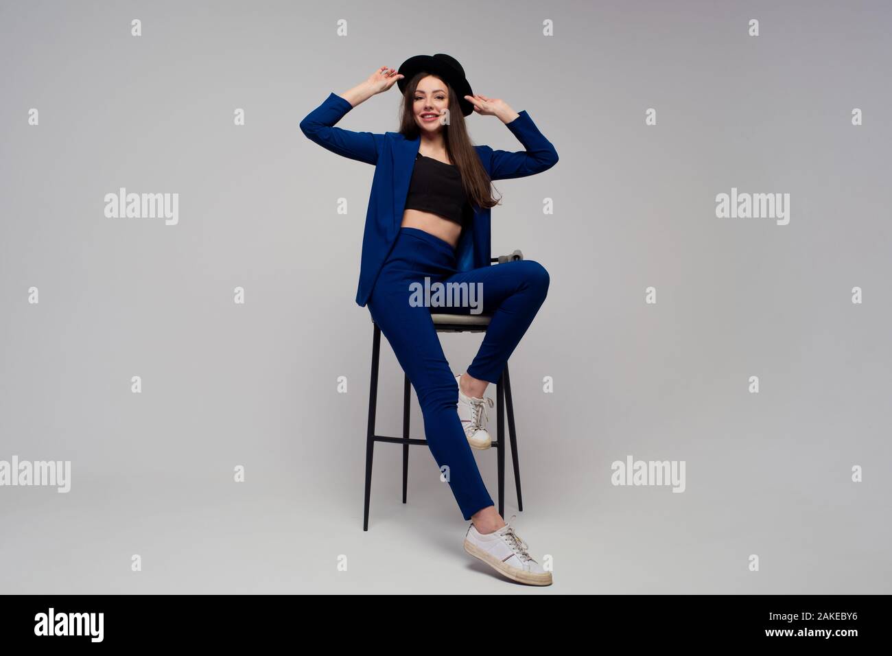 Elegante Geschäftsfrau in dunkelblauem Stranganzug. Positiver Brunette mit Hut, trendigen und modernen Mädchen. Stockfoto