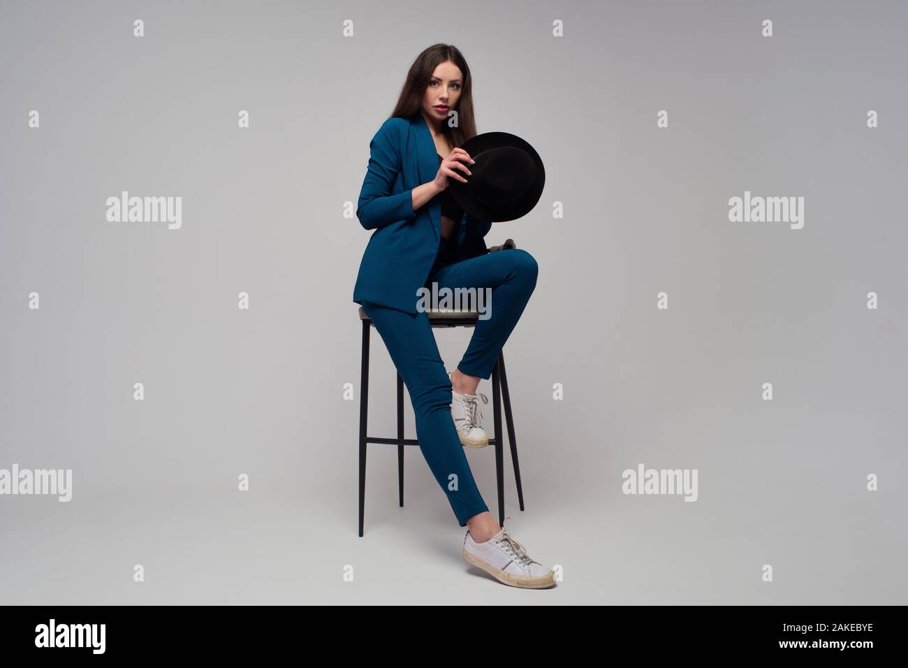 Elegante Geschäftsfrau in dunkelblauem Stranganzug. Positiver Brunette mit Hut, trendigen und modernen Mädchen. Stockfoto