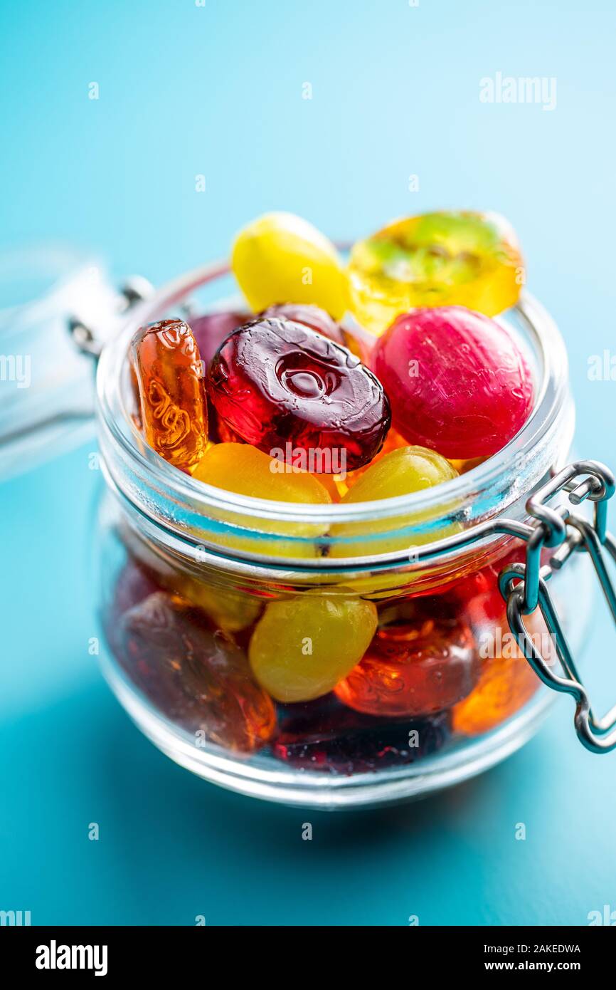 Süße bunte Bonbons im Glas auf blauem Hintergrund. Stockfoto