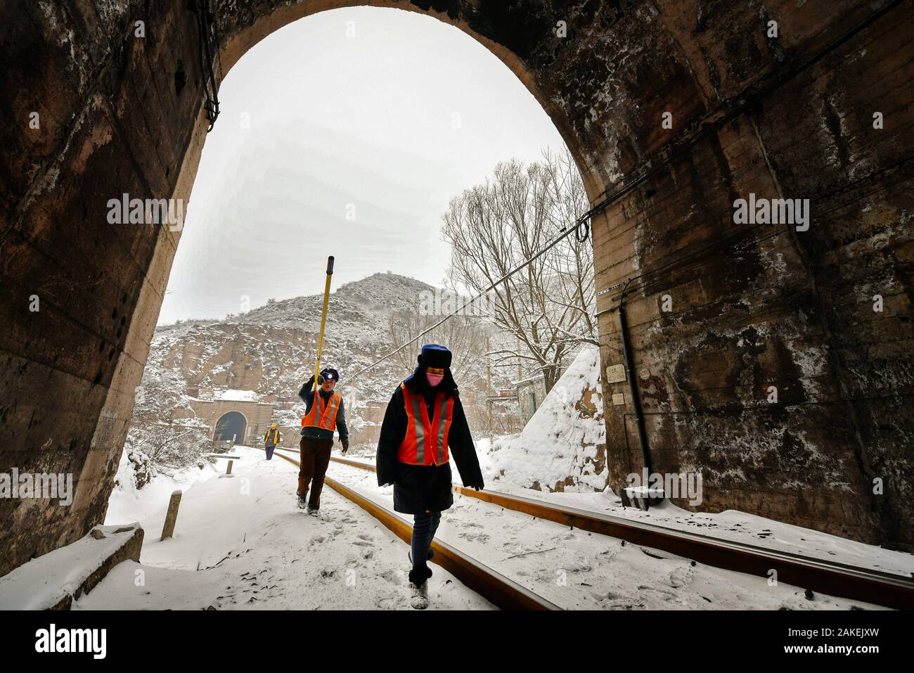 (200109) - - Taiyuan, Januar 9, 2020 (Xinhua) - Qian Fuwang (C) und seine Frau Wang Xinling (R) Spaziergang in einem Eisenbahntunnel der Foyu Abschnitt im Norden der chinesischen Provinz Shanxi, Jan. 8, 2020. Qian Fuwang und seine Frau Wang Xinling Arbeit für Foyu Abschnitt von China Railway Taiyuan Group Co., Ltd. Von Oktober bis Februar des nächsten Jahres aufgrund der niedrigen Temperatur, Eindringen von Wasser in Tunneln kann zum Hängen Eis führen, eine Bedrohung für den Transport sicher. Somit ist das Paar "Hauptaufgabe ist Eis an der Wand hängen von Tunneln zu entfernen. Potentielle Gefahr, die Paare Verhalten 3 Wartung jeden Tag zu beseitigen und Stockfoto