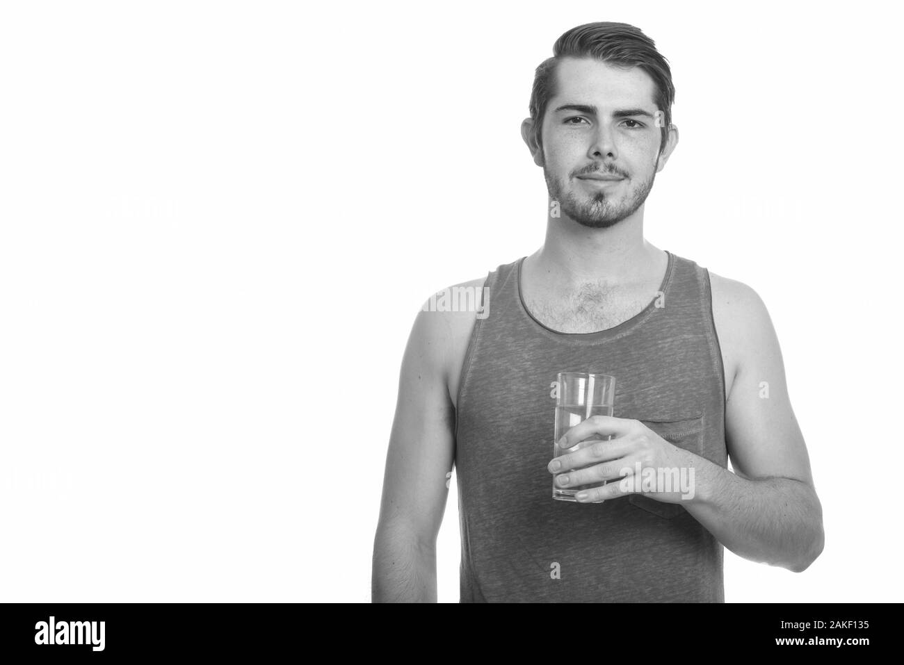 Junger gutaussehender kaukasischer Mann, der ein Glas Wasser bereit für die Turnhalle hält Stockfoto