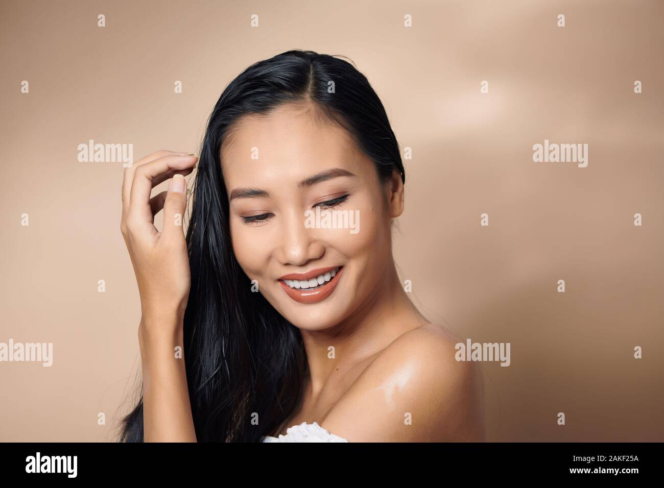 Frau, schön gebräunte Haut glücklich Schönheit Lächeln über grauer Hintergrund Stockfoto