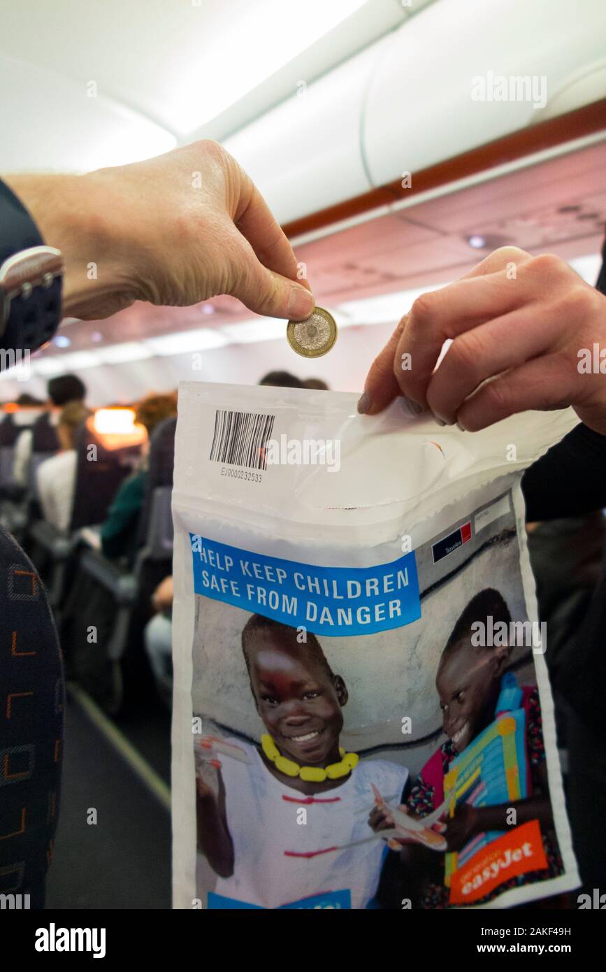 Eine UNICEF-Spendenbeuteltasche, die von einem Mitglied der Kabinenbesatzung auf dem Gang UK eines Flugzeugflugzeugs abgenommen wurde, um kleine Bargeld- und Geldspenden von Passagieren/Passagieren zu sammeln. Geld, das aufgebracht wird, wird in den Kampf gegen Polio gehen. GROSSBRITANNIEN (115) Stockfoto