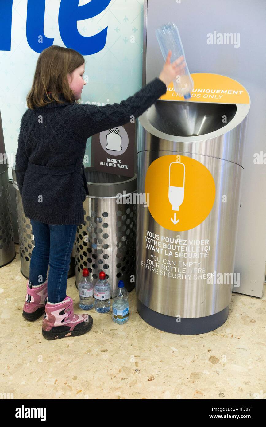 Junge Mädchen im Alter von sieben Jahren gießt Wasser in eine Flüssigkeit  Entsorgen von Flüssigkeiten mit Sicherheit Kontrolle Check/Tasche Suche am  Flughafen in der Schweiz zu entleeren. Nur eine kleine Menge Flüssigkeit