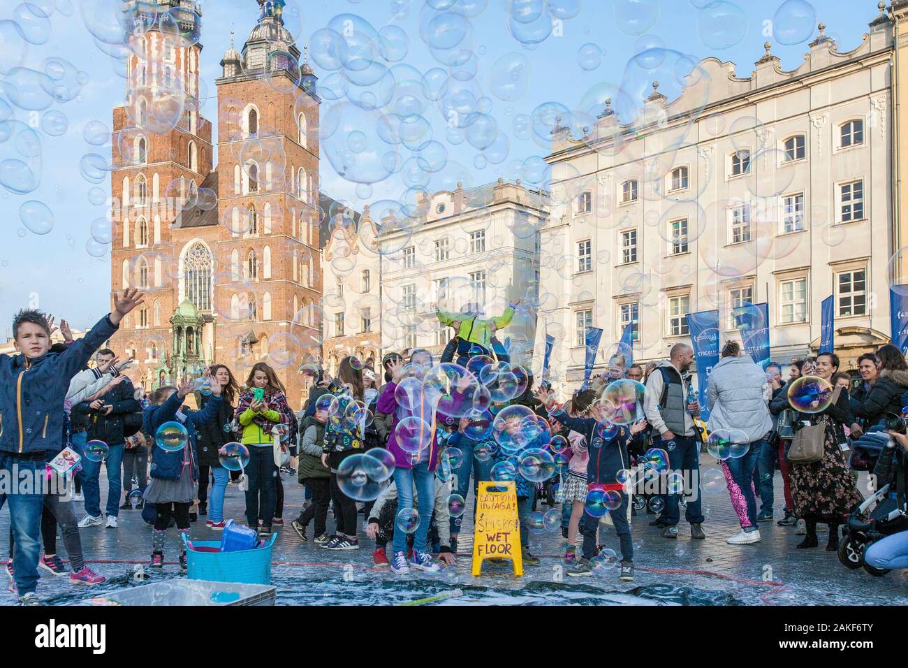 Die Menschen beobachten, wie ein Mann im Rynek Glowny (Hauptmarktplatz) im Zentrum von Krakow (Krakow), Polen, riesige Blasen erzeugt Stockfoto