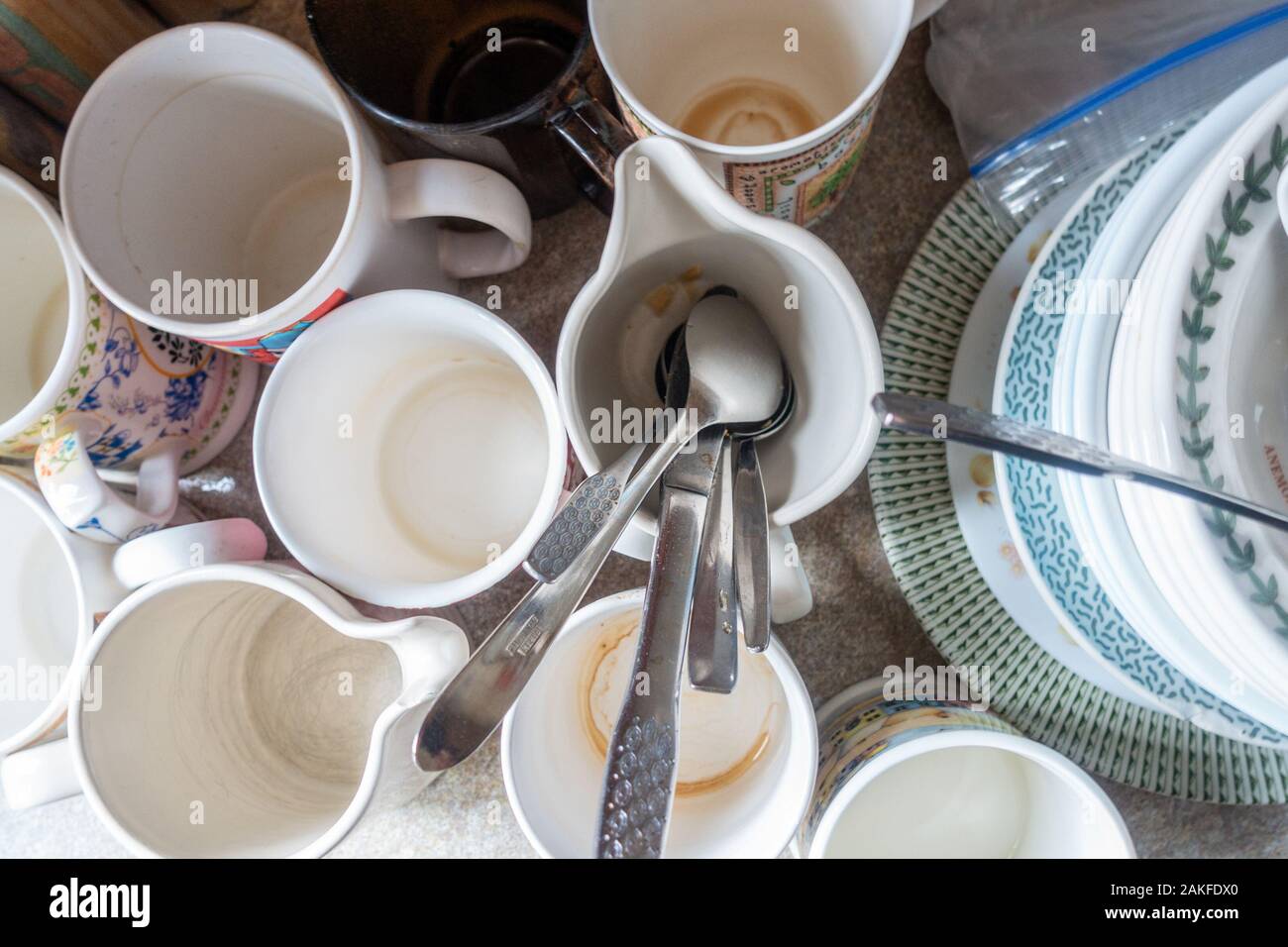 Schmutzige Tassen, Tassen, Teller und Besteck an der Seite einer Spüle  wartet gereinigt und gewaschen Stockfotografie - Alamy