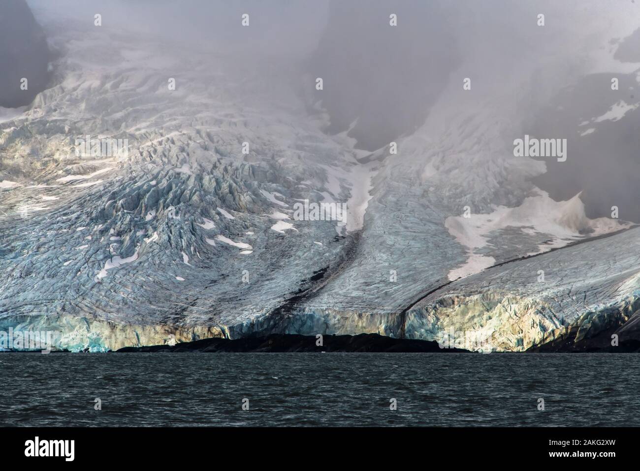 Ein riesiger Gletscher, der von nebligen Bergen herabkommt - eine fantastische Landschaft in der Arktis Stockfoto