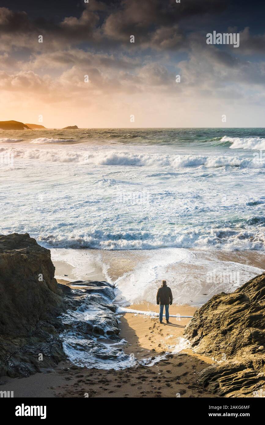 Ein Mann allein am Strand und beobachten die ankommenden Wellen in eine stürmische See an wenig Fistral in Newquay in Cornwall. Stockfoto