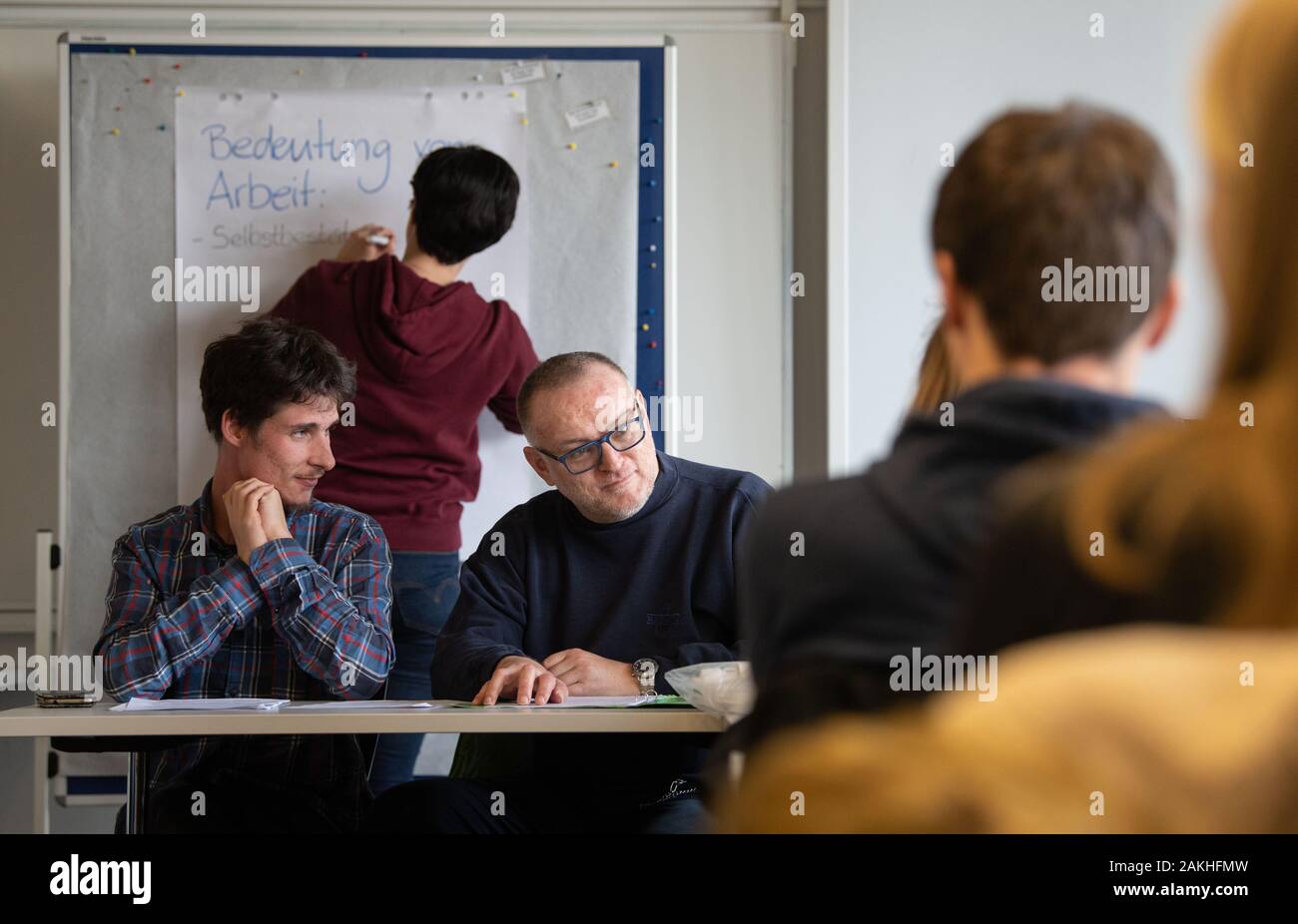 09. Januar 2020, Baden-Württemberg, Ludwigsburg: Michael Gänßmantel (l) und Hartmut Kabelitz (2. v. l), die als geistig behindert, führen ein Seminar im Rahmen des Projektes inklusive Bildung Baden-Württemberg vor Studenten der Sozialen Arbeit und der inklusiven Bildung und Heilpädagogik ohne Handicap, während ein Student an der Flipchart steht und Notizen Schlüsselwörter. Die Studierenden sollen ihre bisher theoretische Kenntnisse durch den Austausch mit Behinderten Bildungsexperten zu erweitern. Das Projekt soll Menschen mit Behinderungen als zu qualifizieren Stockfoto