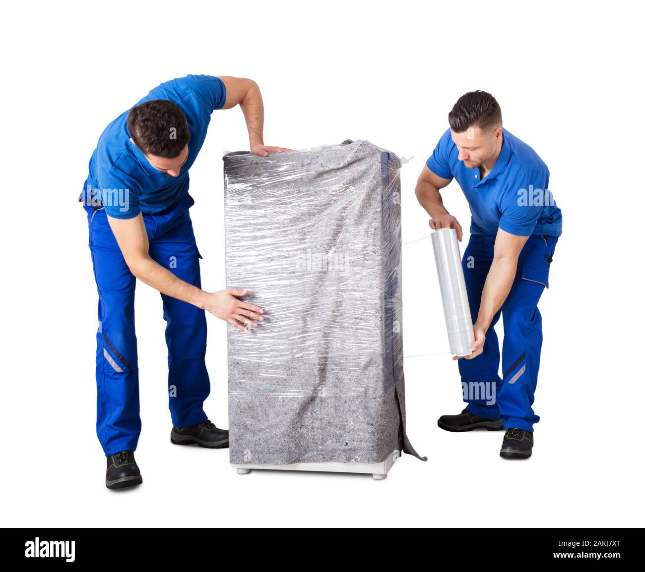 Zwei männliche Movers die Haushaltsgeräte mit Plastikfolie umwickeln auf weißem Hintergrund Stockfoto