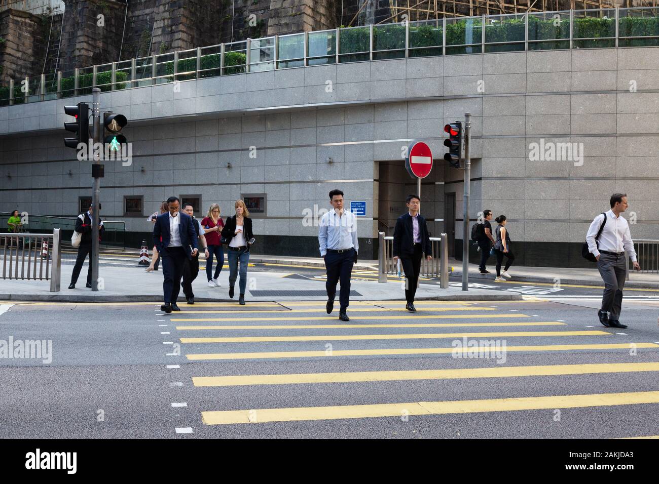 Straßenszene in Hongkong; Menschen, die die Straße an einer Fußgängerüberfahrt, Hong Kong Island, Hong Kong Asia überqueren Stockfoto