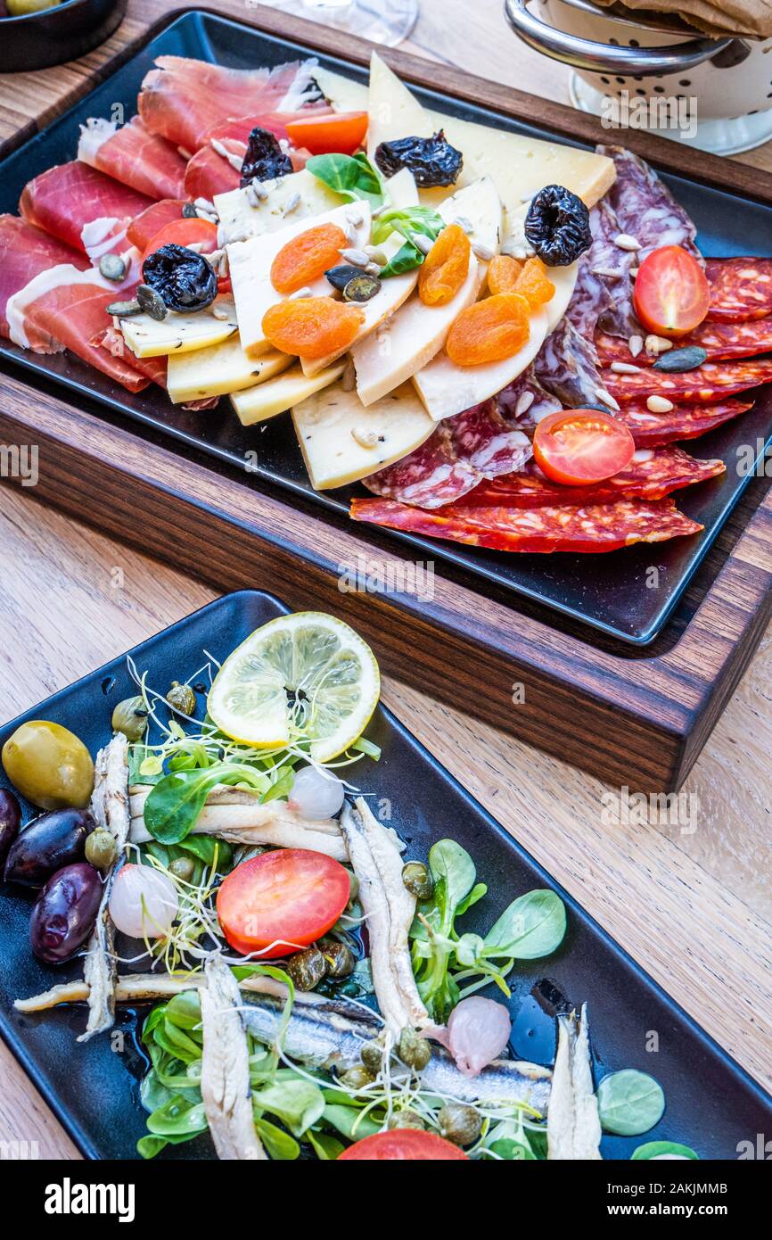 Köstliche, frische Antipasti auf Holzplatte, Salat mit Sardellen und Brot in Papier in dem schönen Restaurant in Italien, Europa Stockfoto