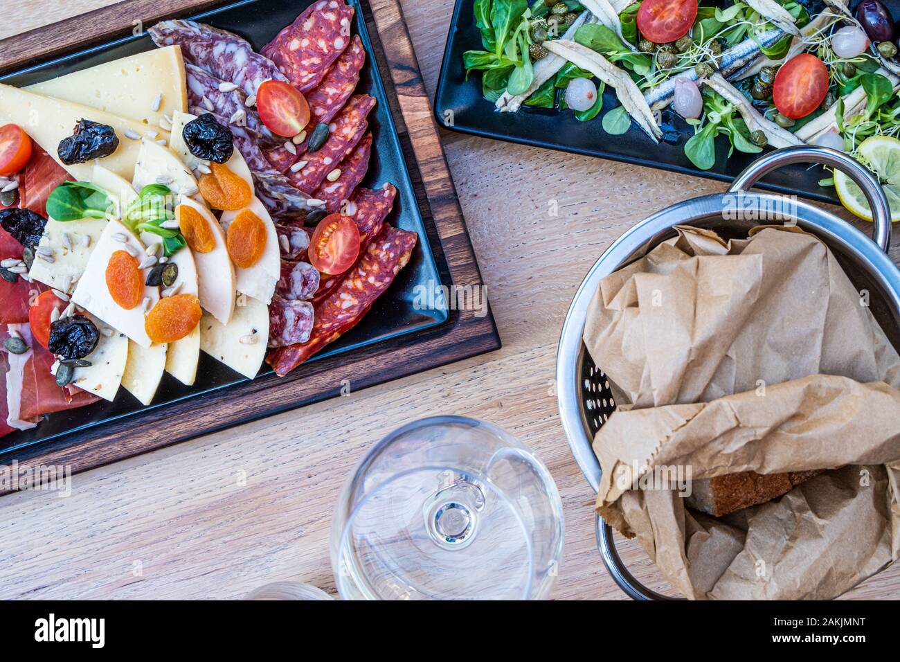 Köstliche, frische Antipasti auf Holzplatte, Salat mit Sardellen und Brot in Papier in dem schönen Restaurant in Italien, Europa Stockfoto