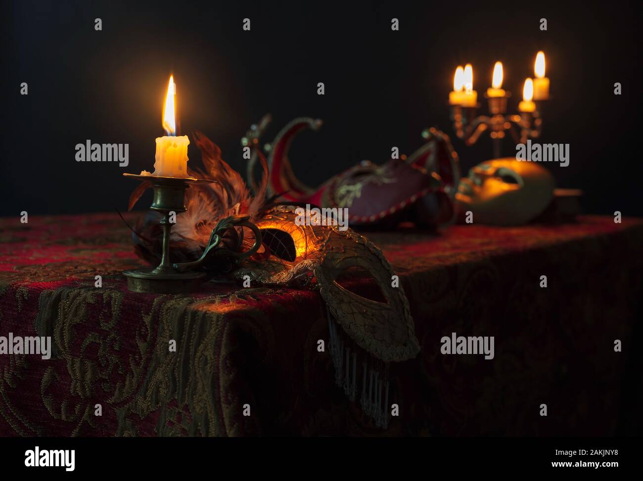 Brennende Kerze in kleinen Messing Leuchter und alten Karneval Masken auf einem dunklen Hintergrund, selektive konzentrieren. Stockfoto
