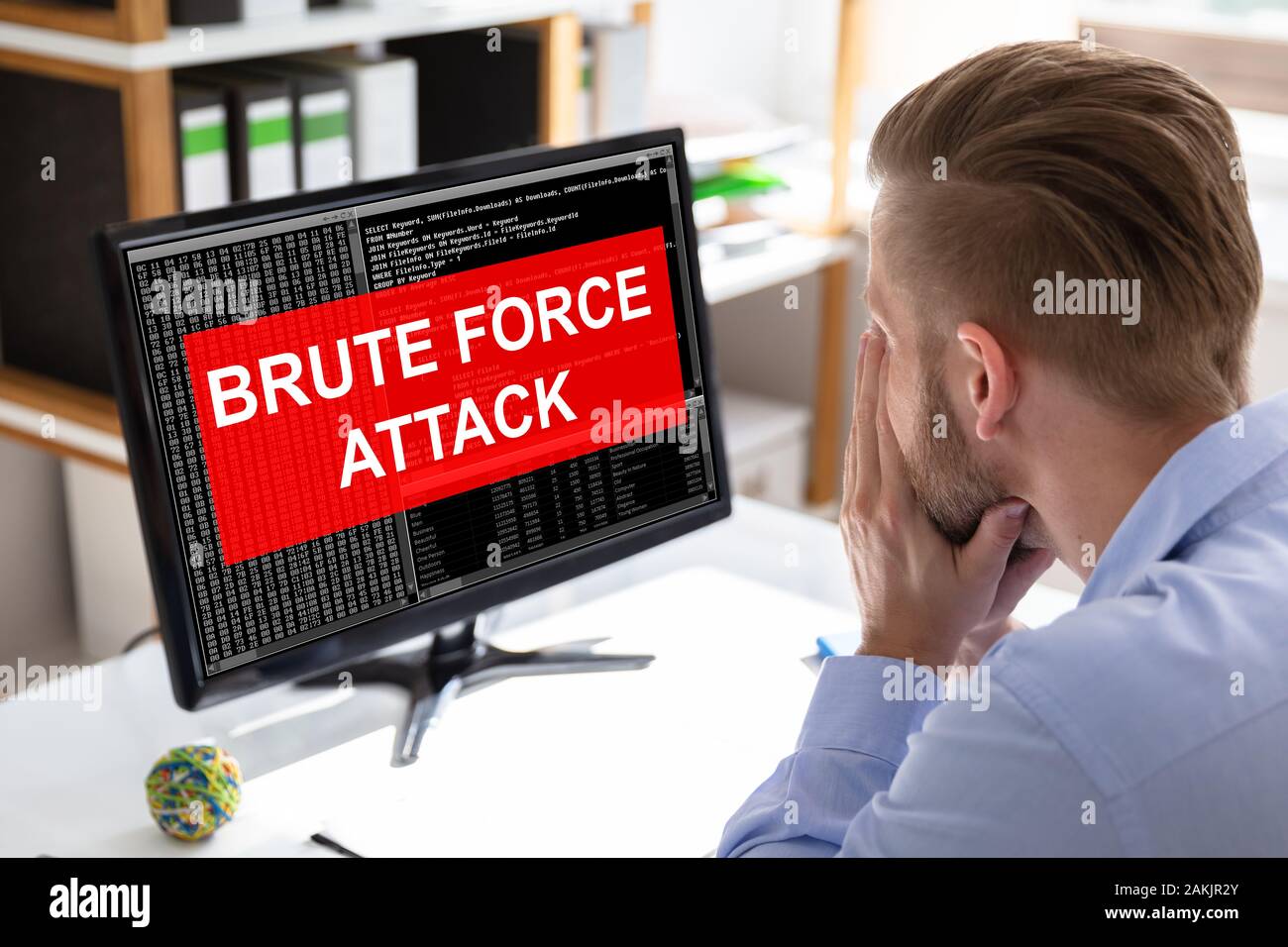 Sider Blick auf einen umgekippten Geschäftsmann auf der Suche nach Bildschirm mit Brute-Force-Angriff Nachricht Stockfoto