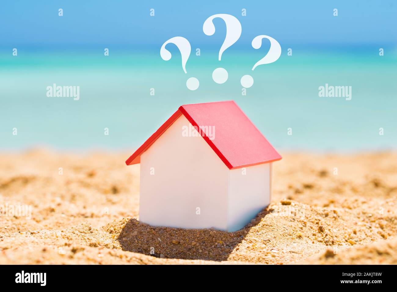 In der Nähe von einem kleinen Haus Modell mit Fragezeichen auf Sand am Strand Stockfoto