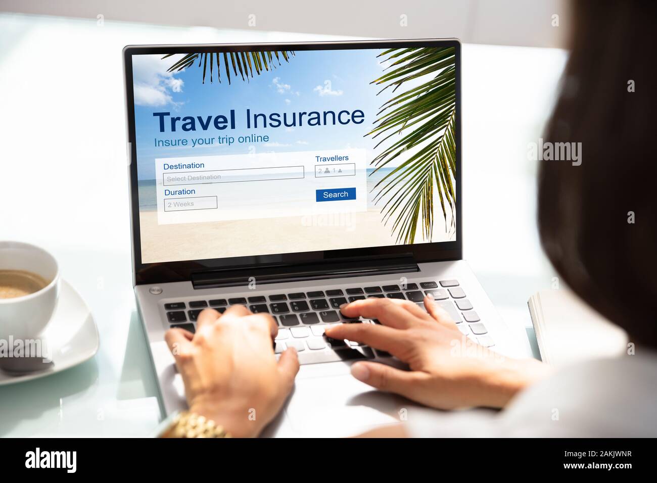 Person mit Laptop über Büro Schreibtisch Arbeiten auf Reisen Versicherung Antrag auf Reise Stockfoto