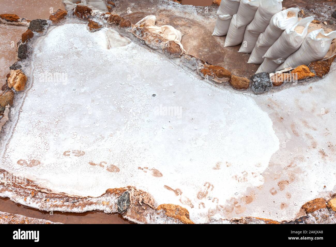 Fußabdrücke auf die Verdampfung Teiche, in der Nähe der gesammelten Säcke Salz. Salineras in Maras, in Peru, in Lateinamerika. Stockfoto