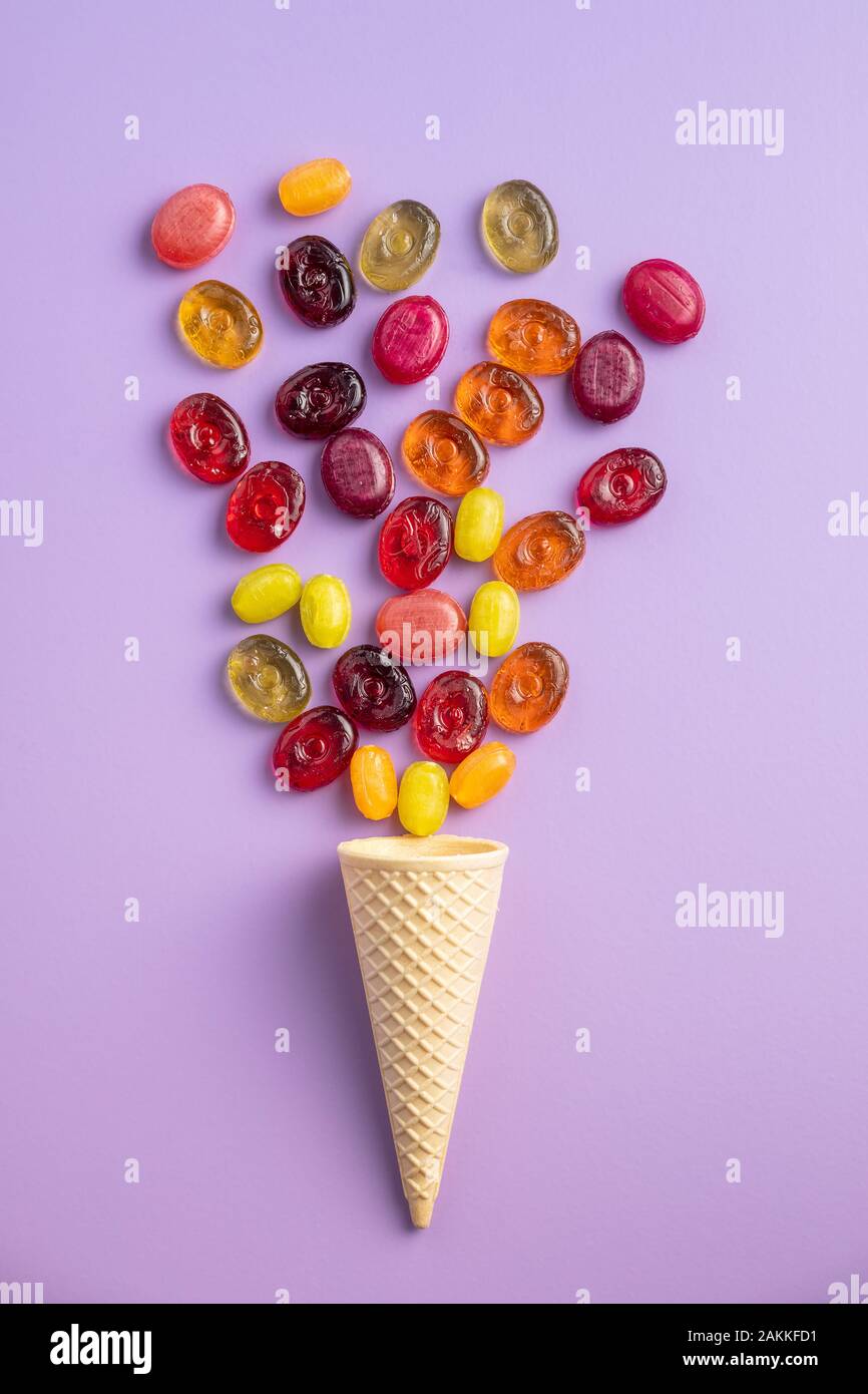 Süße bunte Bonbons in Eis auf Violett Hintergrund. Flache Ansicht. Stockfoto