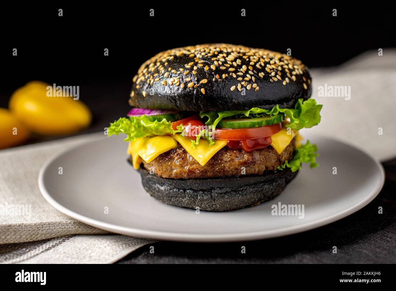 Beef Burger mit einem schwarzen Bun, mit Salat und Mayonnaise und Ketchup auf einem Stück braunem Papier auf einem rustikalen Holztisch von Zähler diente, auf einem dunklen Ba Stockfoto