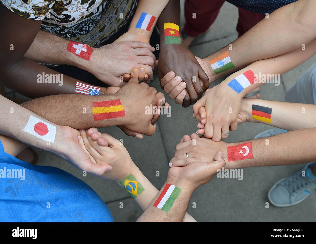 Internationaler Brüder und Schwestern mit Fahnen ihrer Heimat auf ihren Armen in einem Kreis zusammen und halten sich an den Händen bemalt Stockfoto