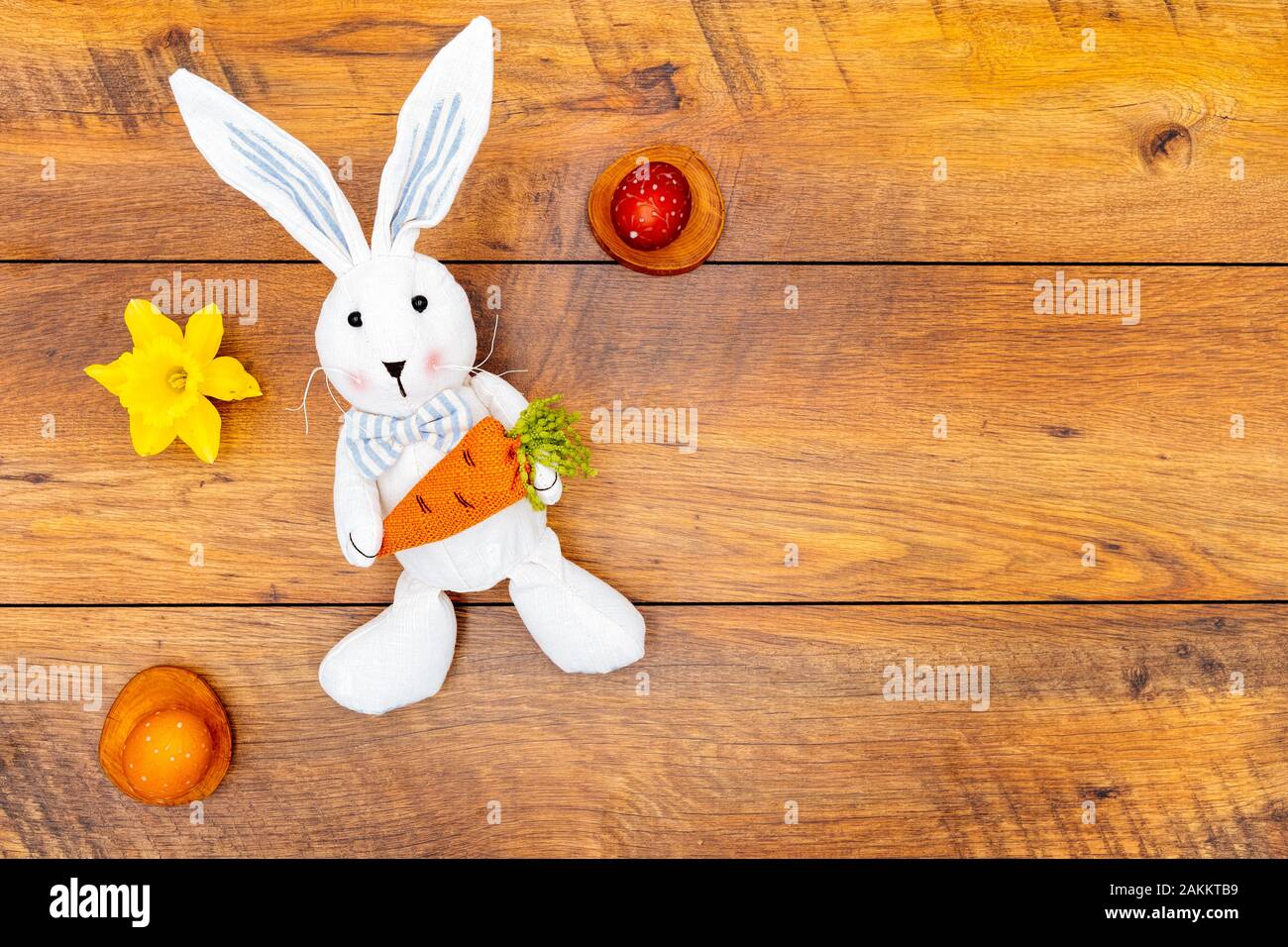 Buntes Wachs bemalte Ostereier in Pastellfarben auf Holzpolstern, Daffodil und Osterhase mit Karotten auf Vintage zurückgewonnenen Eichen-Background-Shirt vie Stockfoto