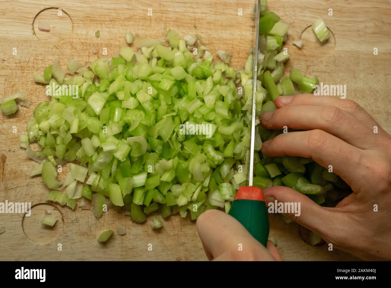 Nahaufnahme von einem Messer hacken Sellerie auf ein Schneidebrett in der Küche mit künstlichem Licht Stockfoto