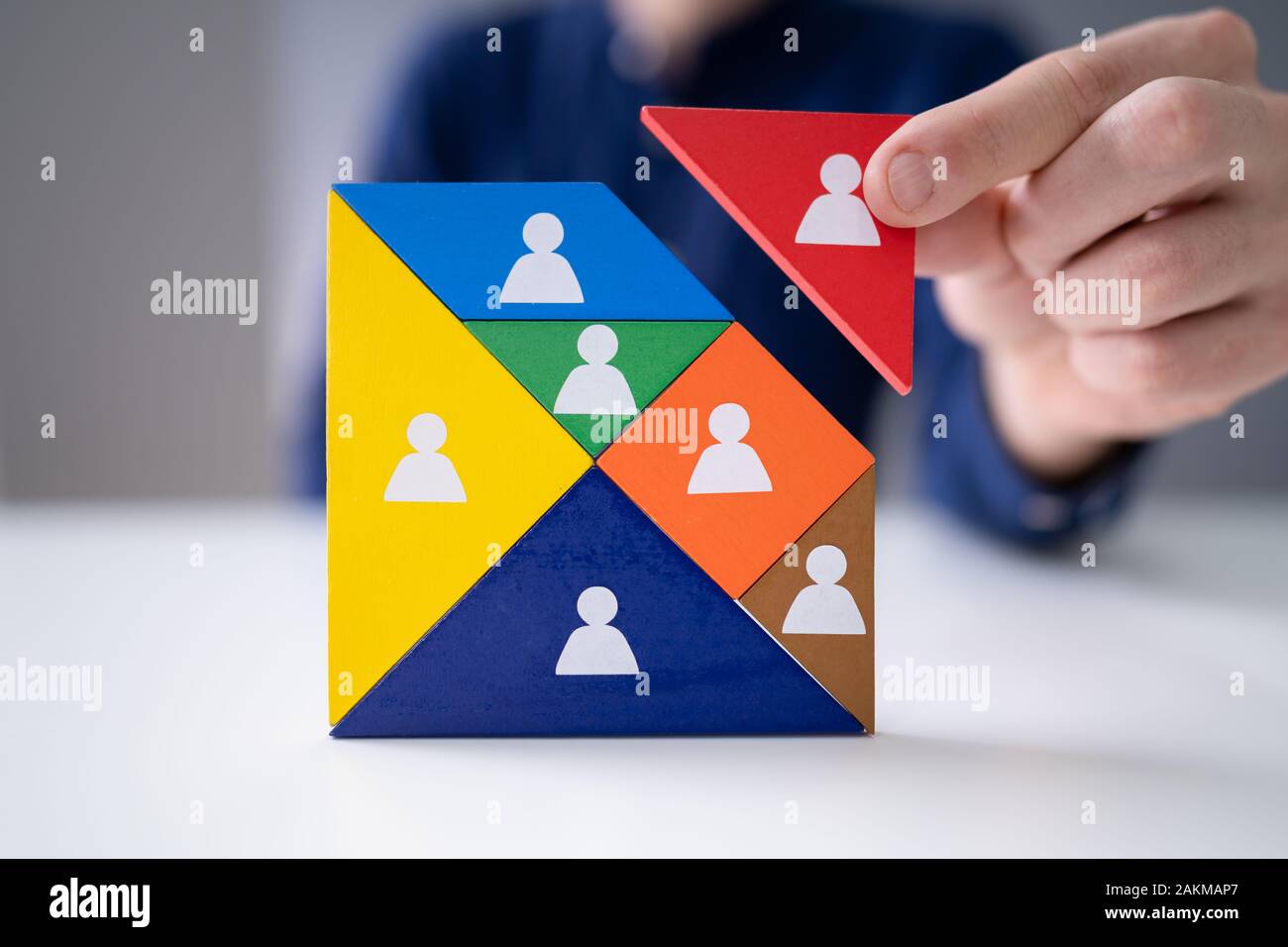 Der Geschäftsmann Hand Gebäude Tangram Square Block mit menschlichen Figuren Stockfoto