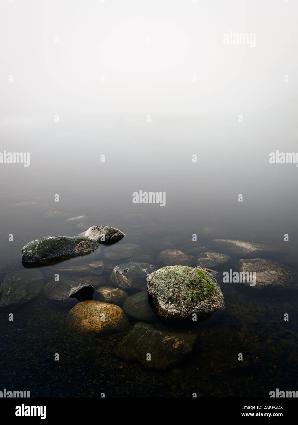 Ruhige und minimalistische Landschaft mit Strandsteinen und nebligen Horizont am Herbstmorgen in Finnland Stockfoto
