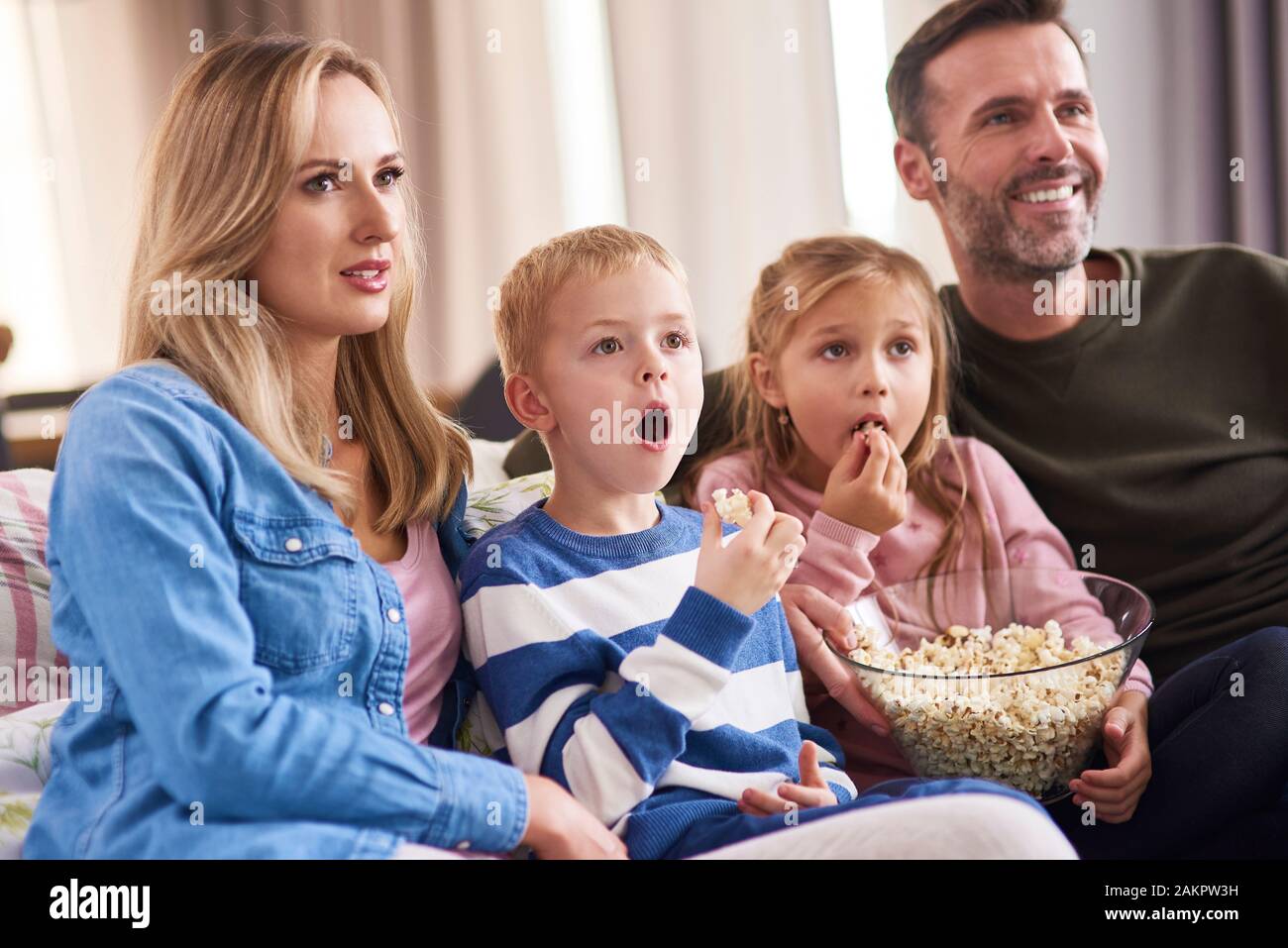 Familie mit zwei Kindern vor dem Fernseher im Wohnzimmer Stockfoto