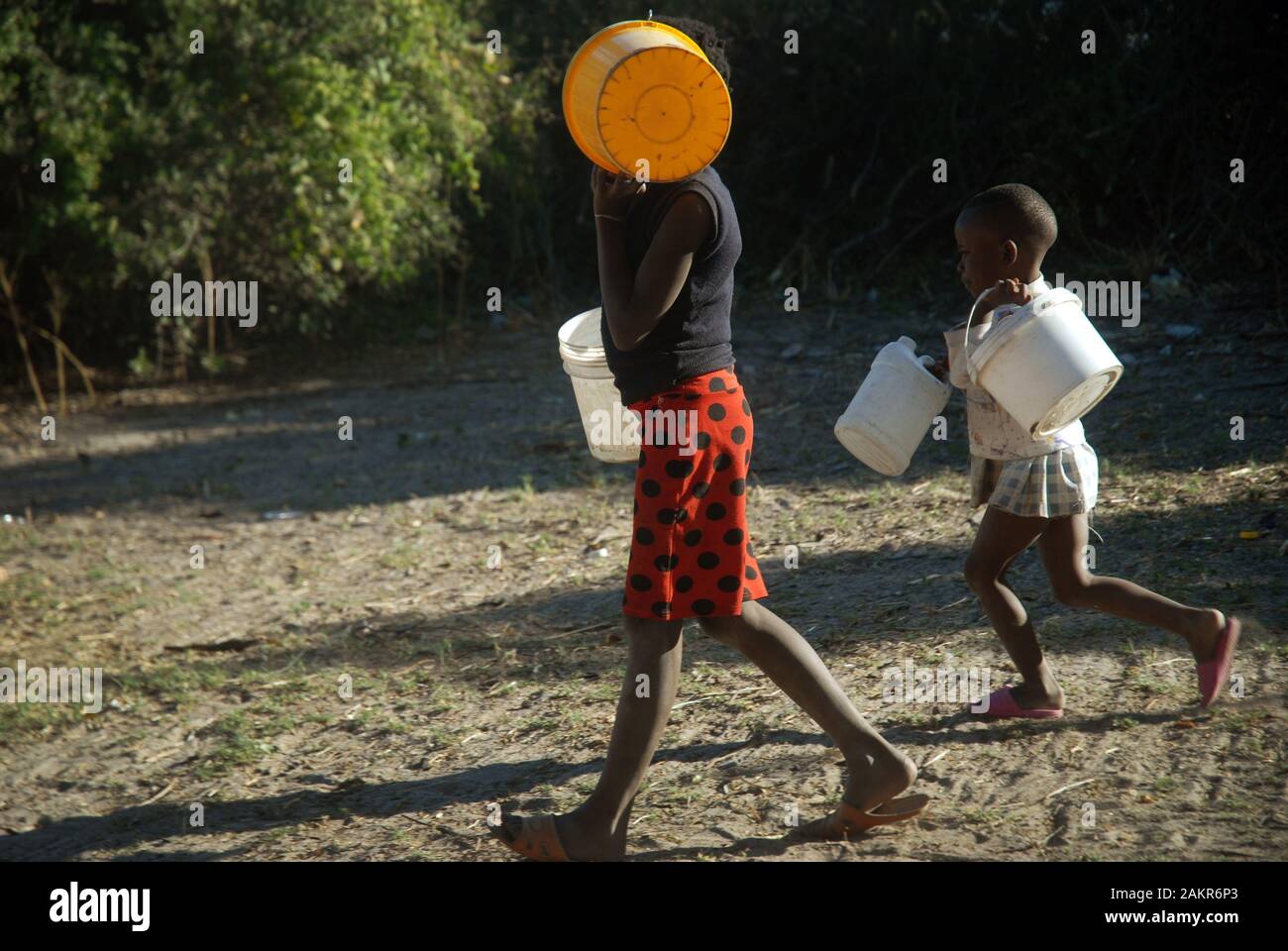 Mädchen sammeln Wasser in Eimern, Mwande, Sambia. Stockfoto