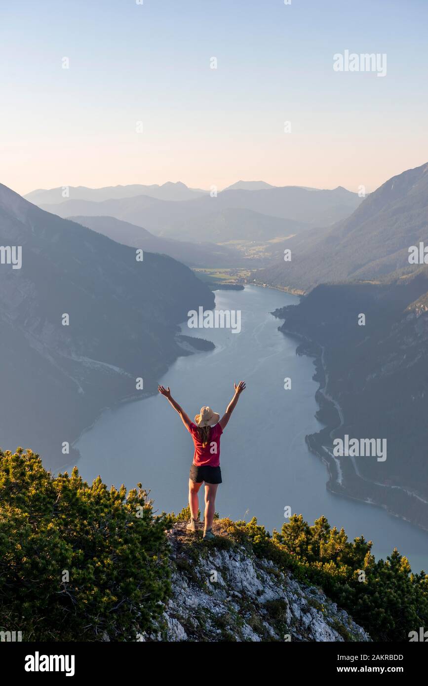 Junge Frau streckt die Arme in die Luft, Aussicht vom Berg Baerenkopf zum Achensee, Tirol, Österreich Stockfoto