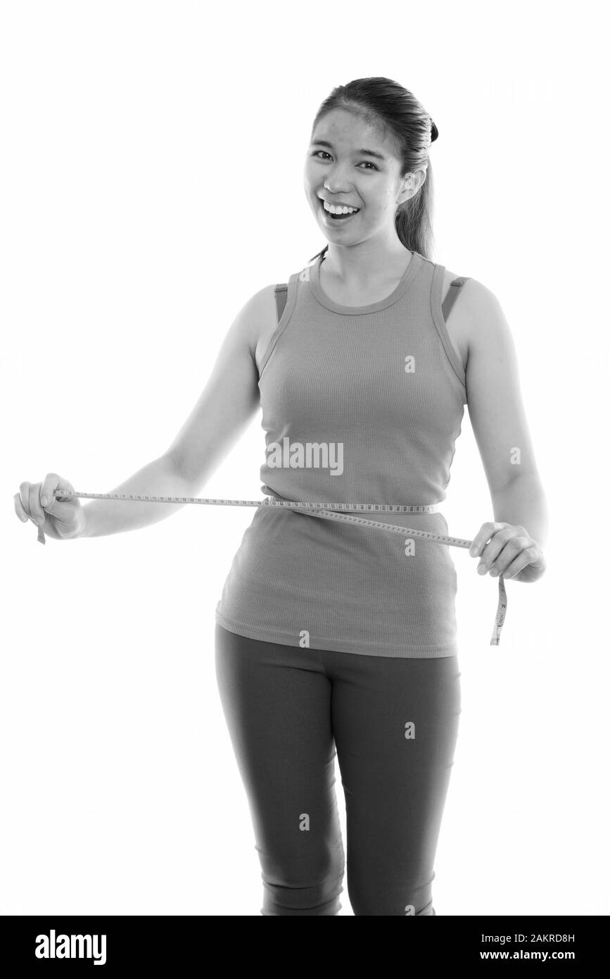 Studio shot von jungen asiatischen Glücklich lächelnde Frau während der Messung Taille bereit für Fitnessraum Stockfoto