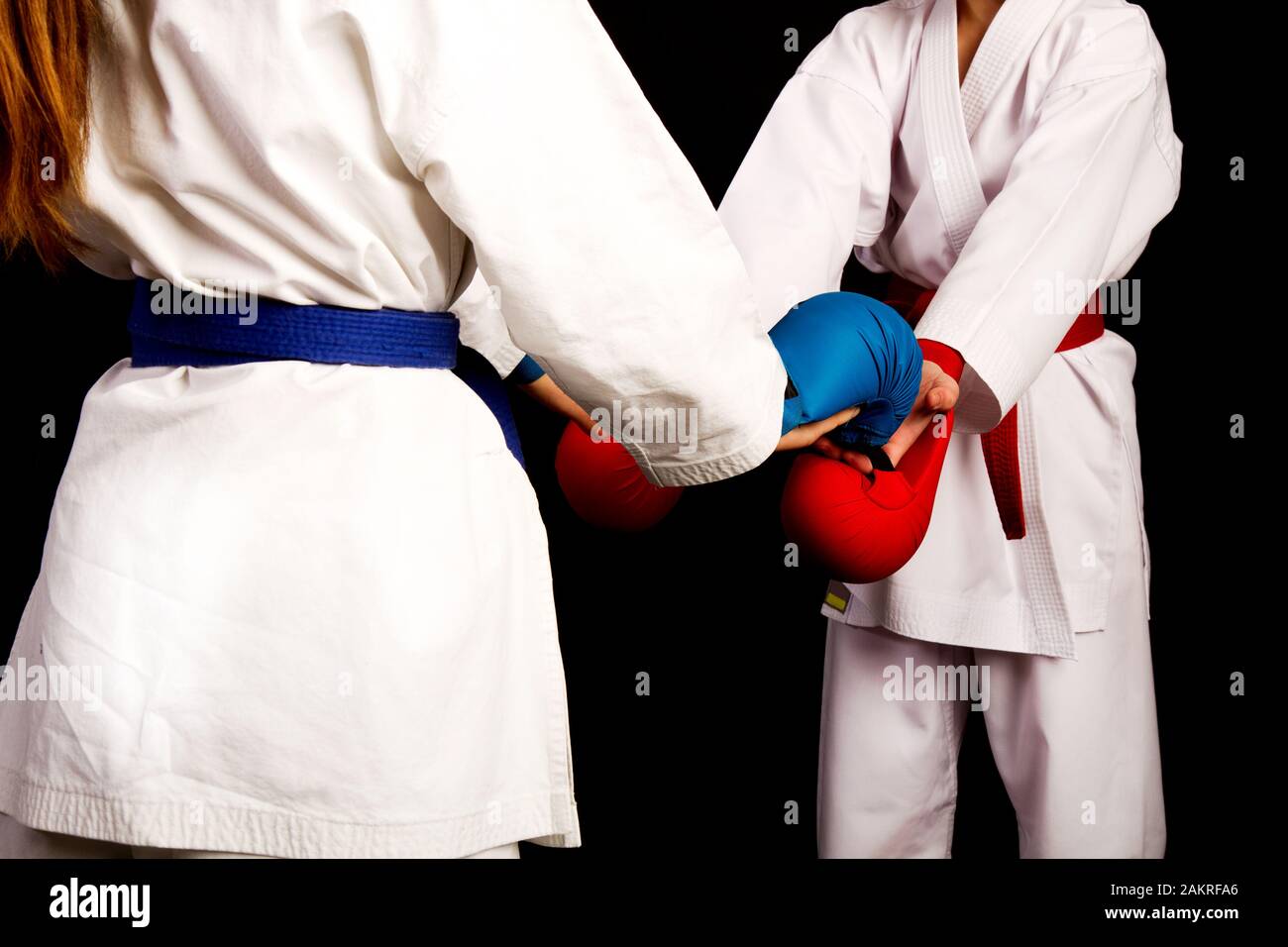 Zwei kleine Karate Frauen in weißen Kimonos, eine in Rot und die andere blau Wettbewerb Ausrüstung schütteln sich die Hände als Zeichen des Respekts vor dem Kampf Aga Stockfoto